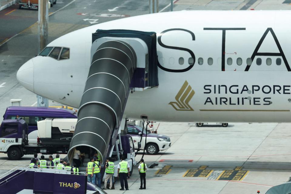 Airport officials gather near the aircraft ladder attached to the Singapore Airlines aircraft for flight SQ321 parked on the tarmac after an emergency landing at Suvarnabhumi International Airport, in Bangkok, Thailand, May 22, 2024.