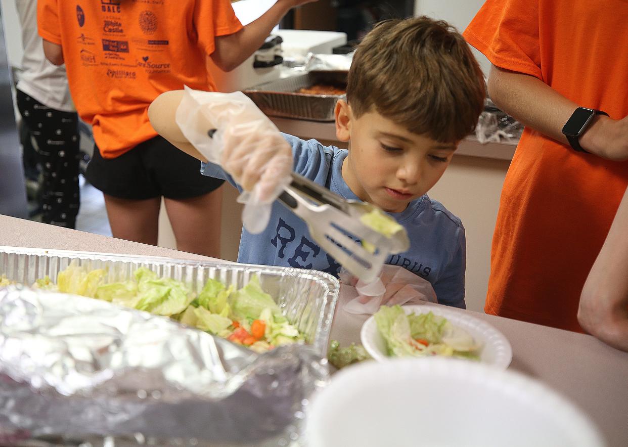 Adam Taha, 9,  makes salads for customers during the Festa Free Summer Lunch Camp at Hilliard Church of Christ on July 8.