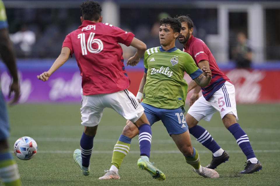 Seattle Sounders forward Fredy Montero (12) kicks the ball from between FC Dallas forward Ricardo Pepi (16) and midfielder Facundo Quignon (5) during the first half of an MLS soccer match Wednesday, Aug. 4, 2021, in Seattle. (AP Photo/Ted S. Warren)