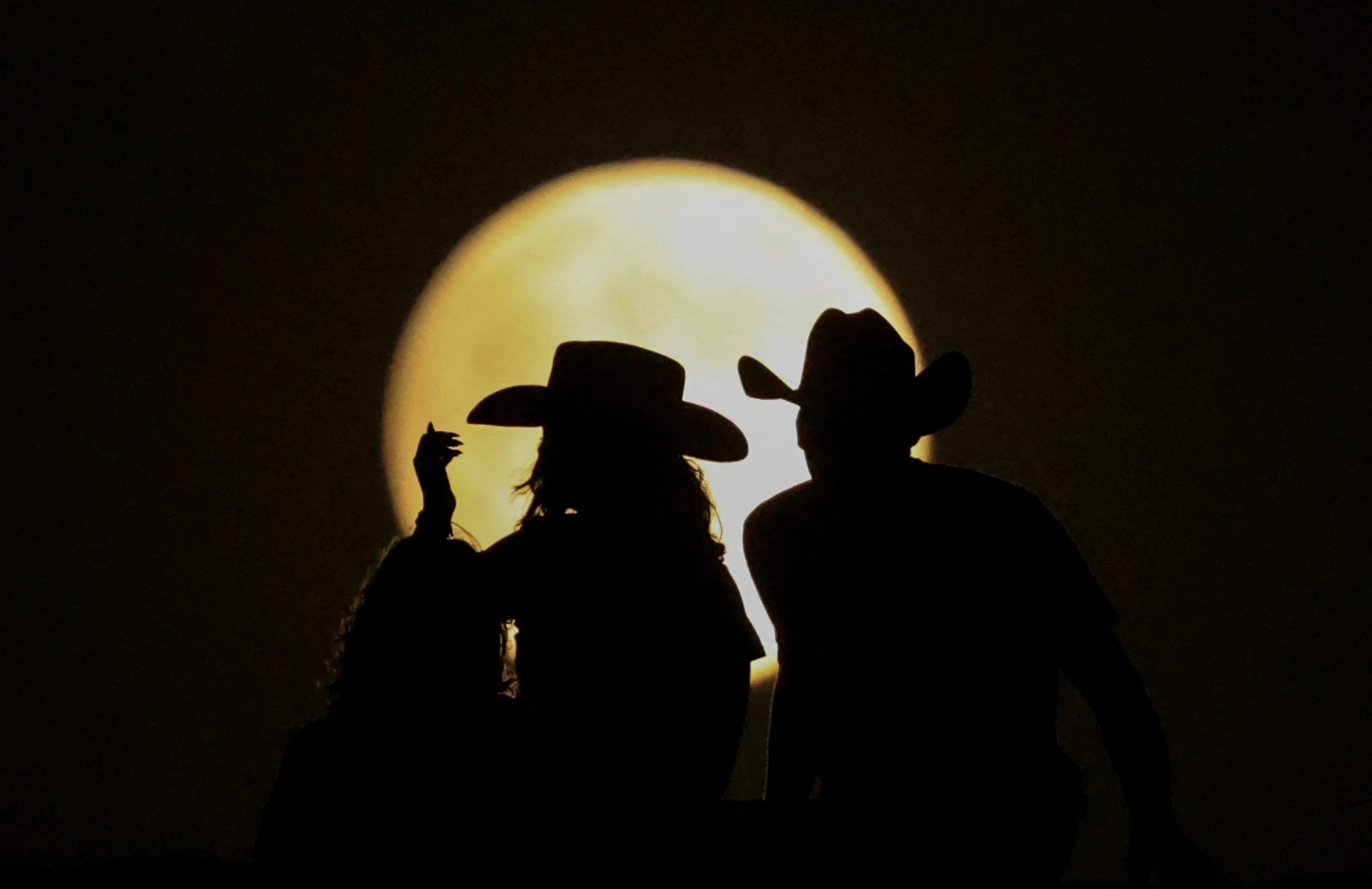 People look at the full moon at the Samalayuca Dunes near Ciudad Juarez, Mexico, on Tuesday.