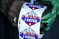 FILE - In this Saturday, Oct. 17, 2020, file photo a poll worker displays "I Voted" stickers during the first day of early voting in Las Vegas. Democrats have kept Nevada in their column in every presidential election since 2004. But political strategists and organizers on the ground warn Nevada is still a swing state. (Steve Marcus/Las Vegas Sun via AP, File)