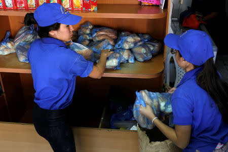 Saleswomen grab bags of bread at a bakery in Caracas, Venezuela March 17, 2017. REUTERS/Marco Bello