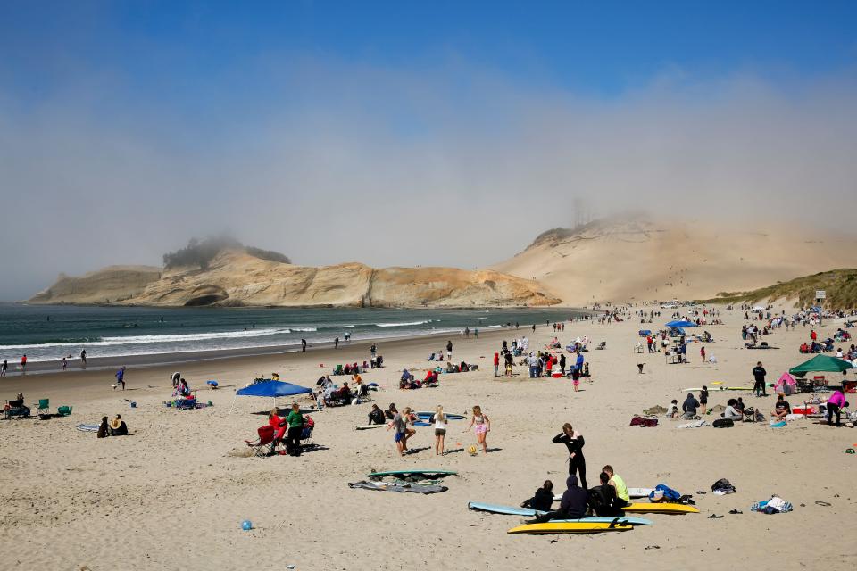 People scatter along the beach on Sunday in Pacific City, Oregon. Crowds were sparse in the morning but continued to grow throughout the day.