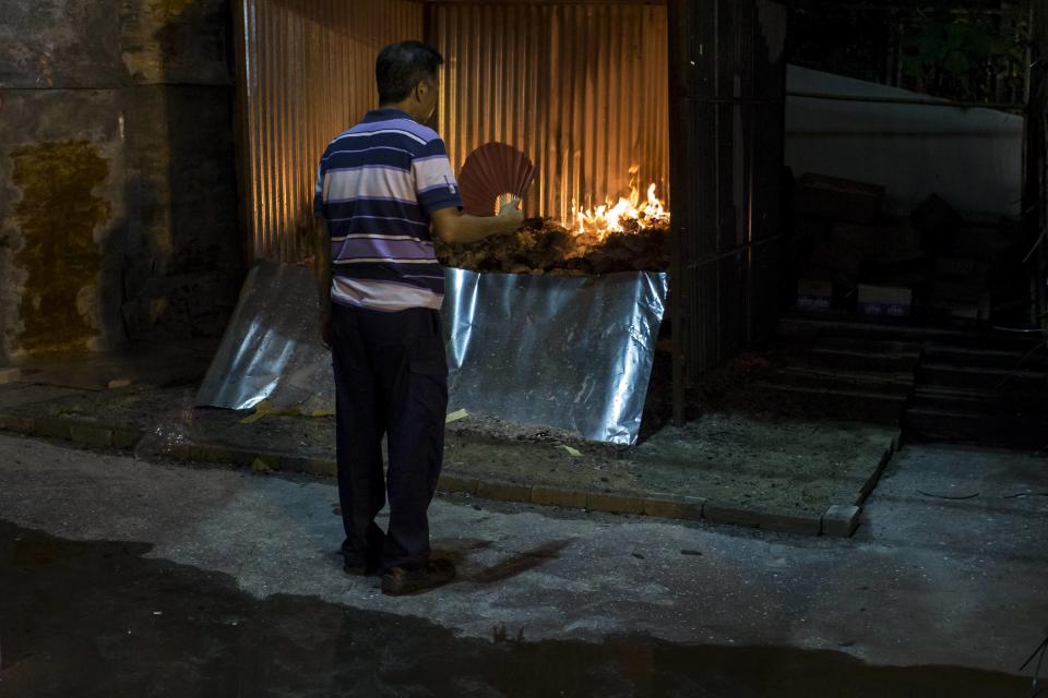 Man looks a furnace burning joss paper money during the Chinese Hungry Ghost Festival in Hong Kong