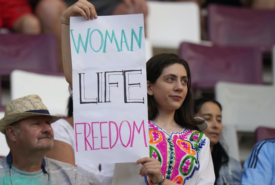 A woman holds up a sign reading ‘Woman Life Freedom’, prior to the soccer match between England and Iran at the FIFA World Cup in Doha, Qatar. (AP Photo/Alessandra Tarantino)