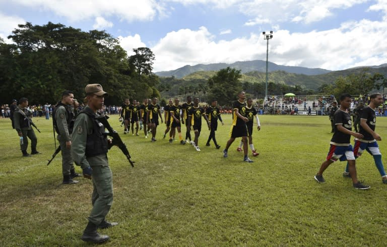 Bolivarian National Guard soldiers armed with AK-47 rifles keep a close watch as inmates of the Gladiadores rugby team enter the pitch during the Penitentiary Rugby Tournament