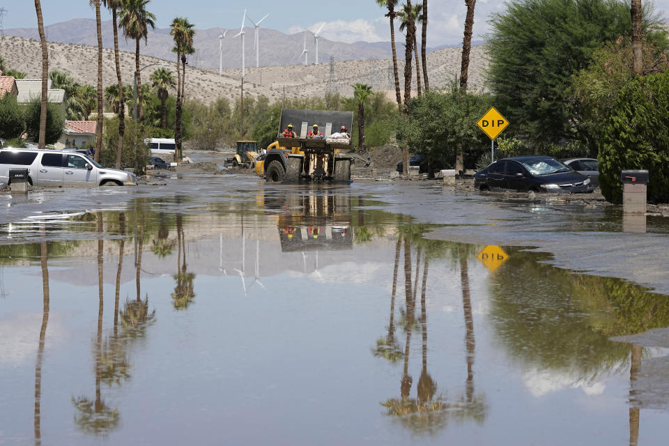 Firefighters use a skip loader to rescue a person from an assisted living center after the street was flooded with mud Monday, Aug. 21, 2023, in Cathedral City, Calif. Scientists figure a natural El Nino, human-caused climate change, a stubborn heat dome over the nation’s midsection and other factors cooked up Hilary’s record-breaking slosh into California and Nevada. (AP Photo/Mark J. Terrill)