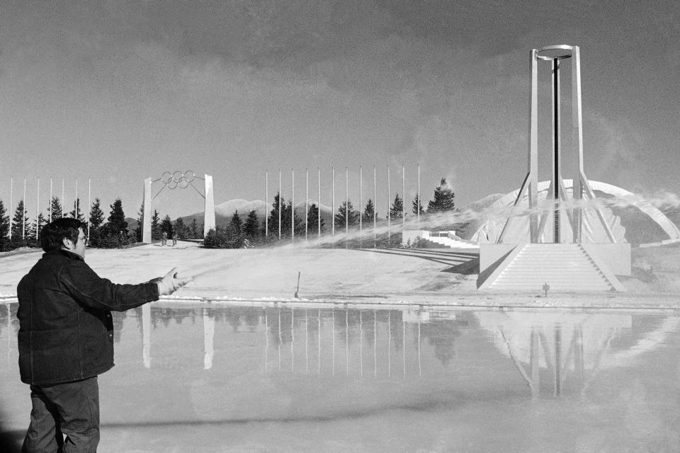 FILE - An employee of Lake Placid village authorities aims a water hose on the artificial lake at the Olympic Stadium in Lake Placid, N.Y., on Feb. 9, 1980, which will serve the skaters during the opening ceremony of the Olympics. (AP Photo, File)