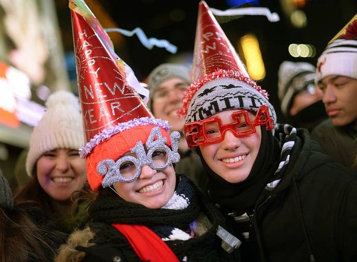 Two people wearing festive "Happy New Year" hats and 2014 glasses celebrating