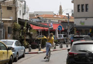 A woman rides a bicycle in the Jaffa neighborhood of Tel Aviv, Israel, Wednesday, April 21, 2021. Historic Jaffa's rapid gentrification in recent years is coming at the expense of its mostly Arab lower class. With housing prices out of reach, discontent over the city’s rapid transformation into a bastion for Israel’s ultra-wealthy is reaching a boiling point. (AP Photo/Sebastian Scheiner)