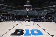 FILE - In this March 12, 2020, file photo, the seating area at Bankers Life Fieldhouse is empty as media and staff mill about in Indianapolis after the Big Ten Conference announced that remainder of the men's NCAA college basketball games tournament was cancelled. Indianapolis city leaders want the college basketball world to know it is open for business. On Friday, Sept. 18, 2020, Indiana Sports Corp, a local, year-round organizing committee, publicly released a 16-page proposal to convert convert about half of the city convention center's exhibition halls and meeting rooms into basketball courts and locker rooms, providing expansive safety measures and daily COVID-19 testing. (AP Photo/Michael Conroy, File)