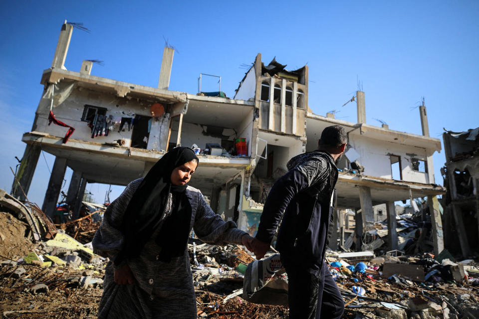 Image: Palestinian people walk past a destroyed building in the Al-Maghazi refugee camp (AFP - Getty Images)