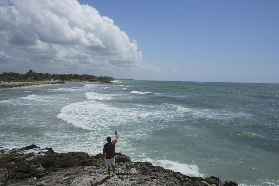 Un hombre toma video desde la costa rocosa de la playa Mirador antes de la llegada del huracán Beryl, el jueves 4 de julio de 2024, en Tulum, México. (AP Foto/Fernando Llano)