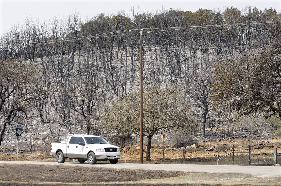 A truck drives along FM 1148 near Possum Kingdom Lake on Saturday, April 16, 2011 past a hillside scorched in fires fueled by high winds.