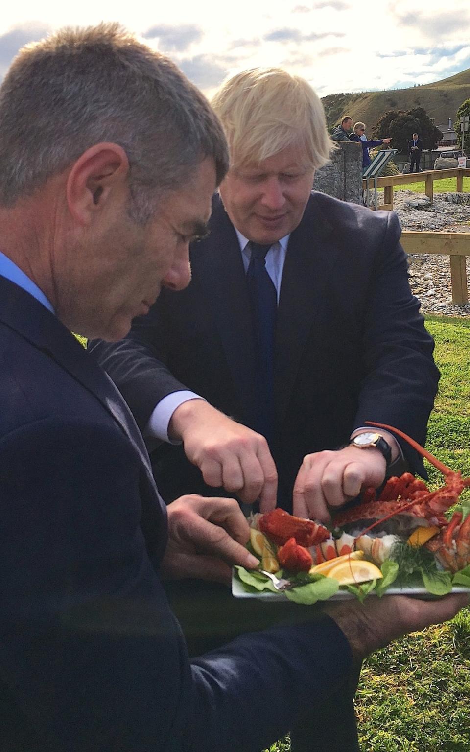 Boris Johnson eats crayfish with New Zealand Civil Defence Minister Nathan Guy - Credit: Reuters