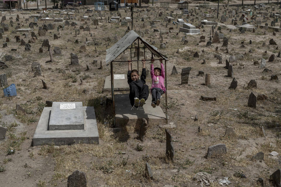 Afghan children play among the graves at a cemetery in Kabul, Afghanistan, Friday, May 27, 2022. There are cemeteries all over Afghanistan's capital, Kabul, many of them filled with the dead from the country's decades of war. They are incorporated casually into Afghans' lives. They provide open spaces where children play football or cricket or fly kites, where adults hang out, smoking, talking and joking, since there are few public parks. (AP Photo/Ebrahim Noroozi)