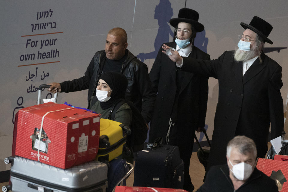People wearing protective face masks arrive at the Ben Gurion Airport near Tel Aviv, Israel, Monday, Nov. 1, 2021. Israel on Monday began welcoming individual tourists for the first time since the onset of the coronavirus pandemic. (AP Photo/Ariel Schalit)