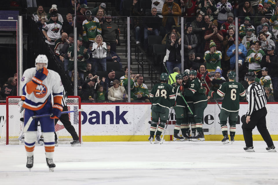 Minnesota Wild center Connor Dewar (26) is surrounded by teammates after scoring during the second period of an NHL hockey game against the New York Islanders, Monday, Jan. 15, 2024, in St. Paul, Minn. (AP Photo/Stacy Bengs)