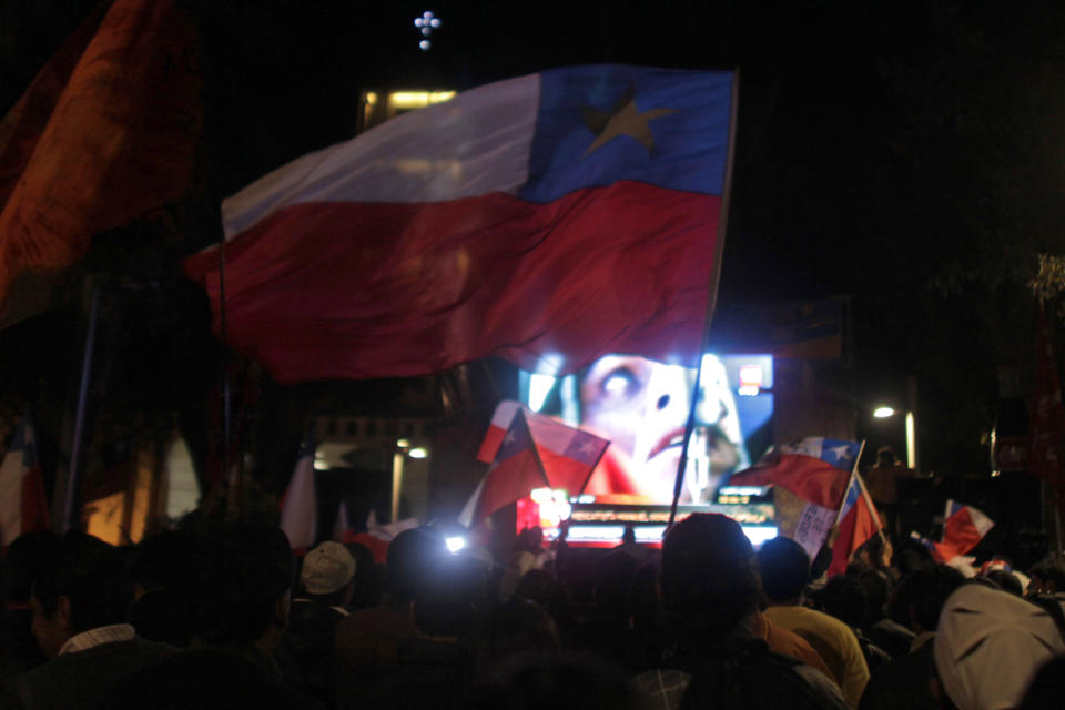 ARCHIVO - En esta foto de archivo del 12 de octubre de 2010, la gente celebra mientras observa en una televisión gigante a un primer rescatista ingresando a un túnel de escape en la mina San José para iniciar el rescate de los 33 mineros atrapados en Copiapó, Chile, el miércoles 5 de agosto de 2020. (AP Foto/Dario Lopez-Mills, Archivo)