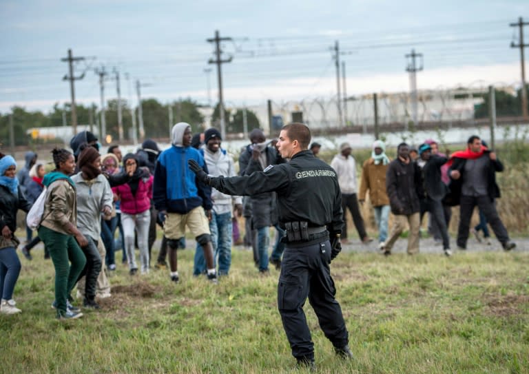 A policeman confronts migrants trying to reach the Channel Tunnel in Coquelles near Calais, northern France, late on July 29, 2015