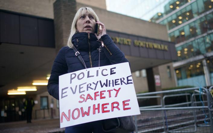 Une femme se tient devant le tribunal de la Couronne de Southwark avec une pancarte indiquant : « La police partout, la sécurité nulle part » – Yui Mok/PA