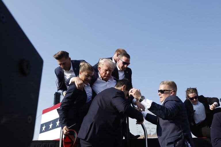  El candidato presidencial republicano, el expresidente Donald Trump, es apresurado fuera del escenario durante un mitin el 13 de julio de 2024 en Butler, Pensilvania. 