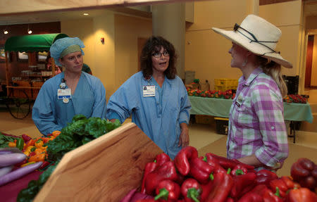 Amanda Sweetman, project manager, The Farm, talks with two Registered Nurses about the fresh vegetables for sale in the main lobby at Saint Joseph Mercy hospital in Ypsilanti, Michigan, U.S., August 23, 2017. Picture taken august 23, 2017. REUTERS/Rebecca Cook