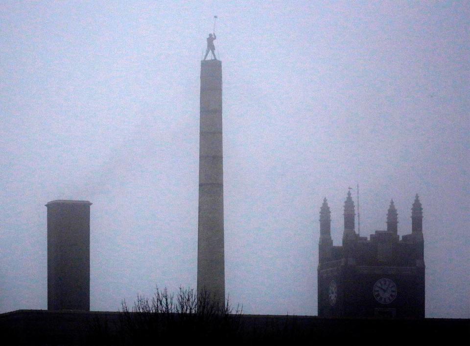 FILE - The spires of Central High School, right, and the sweep atop the historic smoke stack by the Henry Jung Apartment complex are silhouettes in the fog, Tuesday, March 15, 2022, in Sheboygan, Wis.