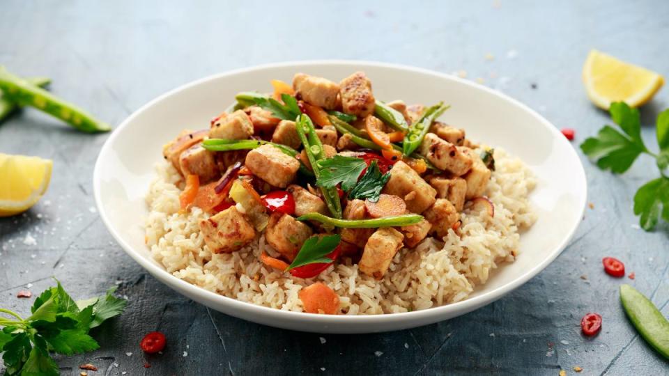 Plant Based Diet For Weight Loss: Vegetarian meat free mycoprotein pieces vegetable stir fry, brown rice served in white plate.