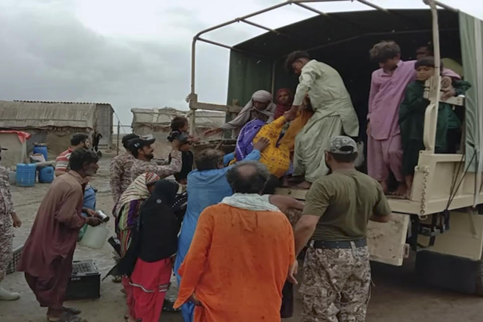 In this picture released by Pakistan's Sindh Rangers, paramilitary soldiers help to evacuate people from a village due to Cyclone Biparjoy approaching, at a costal area of Thatta district, in Pakistan's Sindh province, Tuesday, June 13, 2023. Pakistan's army and civil authorities are planning to evacuate 80,000 people to safety along the country's southern coast, and thousands in neighboring India sought shelter ahead of Cyclone Biparjoy, officials said. (Pakistan's Sindh Rangers via AP)