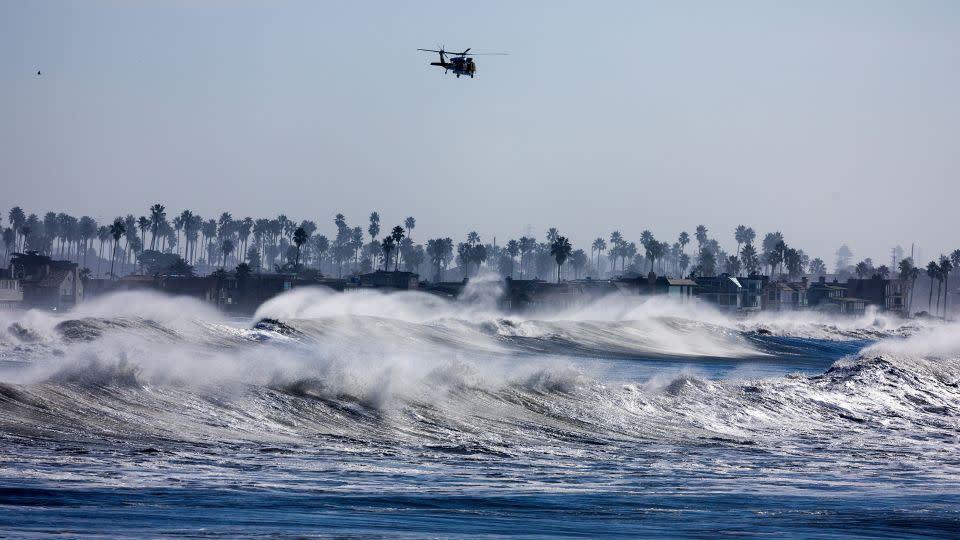 A Ventura County, California, fire helicopter patrols the coastline over heavy surf south of Ventura Pier on December 28. - Brian van der Brug/Los Angeles Times/Getty Images