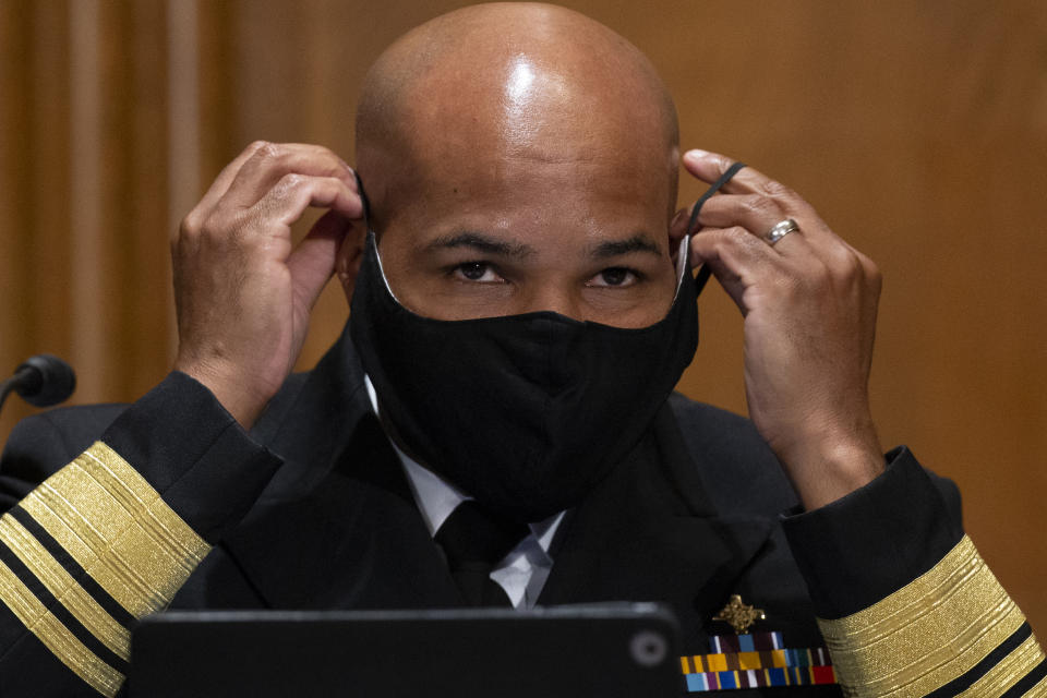 Surgeon General Jerome Adams puts on a face mask after a Senate Health, Education, Labor and Pensions Committee hearing to discuss vaccines and protecting public health during the coronavirus pandemic on Capitol Hill, Wednesday, Sept. 9, 2020, in Washington. (Michael Reynolds/Pool via AP)