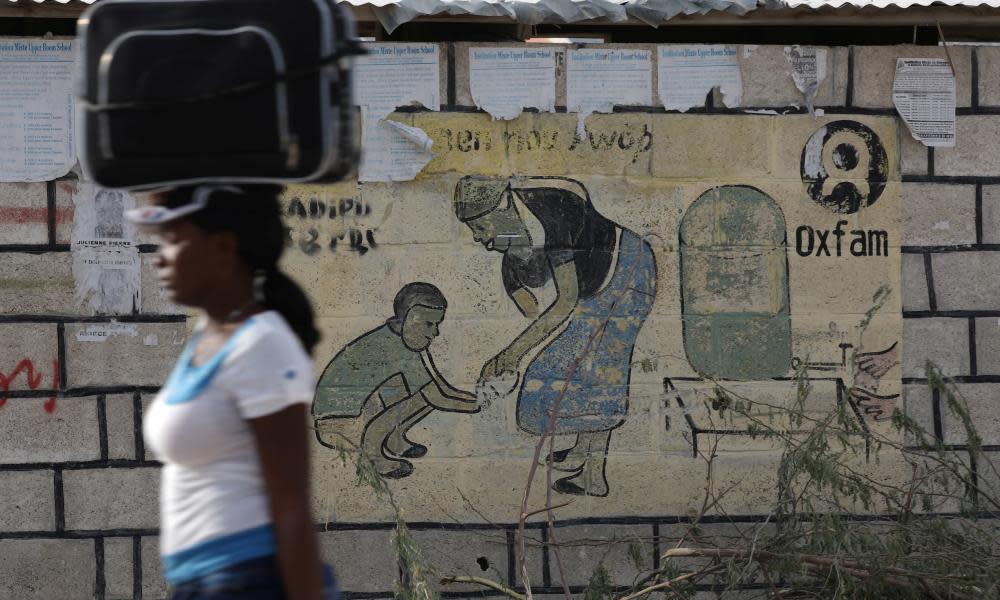 Woman walks past Oxfam sign near Port-au-Prince, Haiti