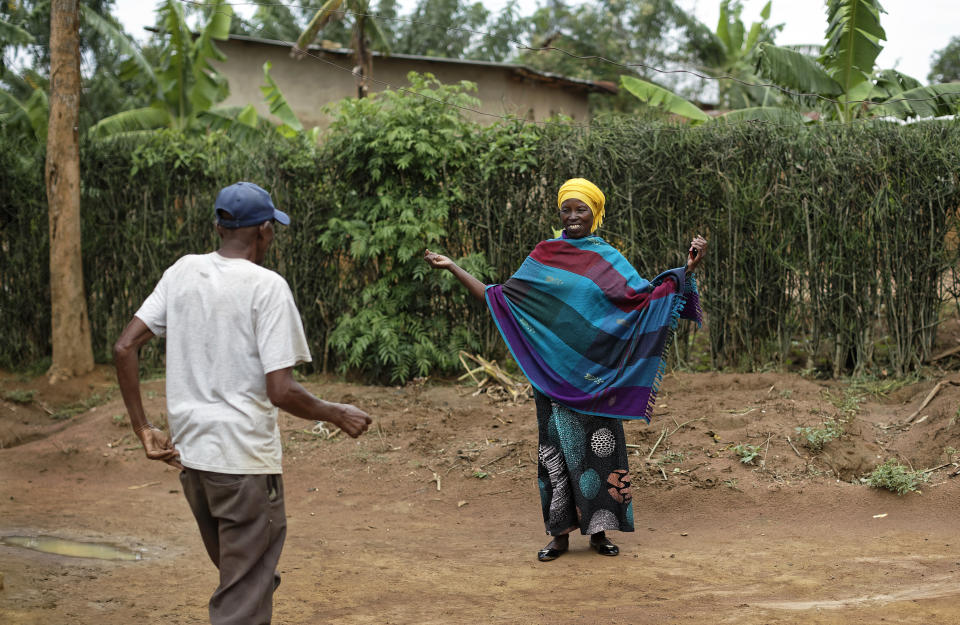 In this photo taken Thursday, April 4, 2019, genocide survivor Laurencia Mukalemera, right, a Tutsi, greets Tasian Nkundiye, left, a Hutu who murdered her husband and spent eight years in prison for the killing and other crimes, at Nkundiye's home in the reconciliation village of Mbyo, near Nyamata, in Rwanda. Twenty-five years after the genocide the country has six "reconciliation villages" where convicted perpetrators who have been released from prison after publicly apologizing for their crimes live side by side with genocide survivors who have professed forgiveness. (AP Photo/Ben Curtis)