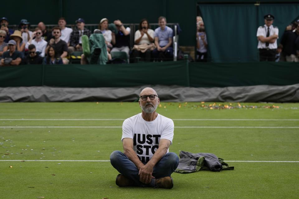 FILE - A Just Stop Oil protester sits on Court 18 on day three of the Wimbledon tennis championships in London, July 5, 2023. Climate activists have spraypainted a superyacht, blocked private jets from taking off and plugged holes in golf courses this summer as part of an intensifying campaign against the emissions-spewing lifestyles of the ultrawealthy. (AP Photo/Alastair Grant, File)