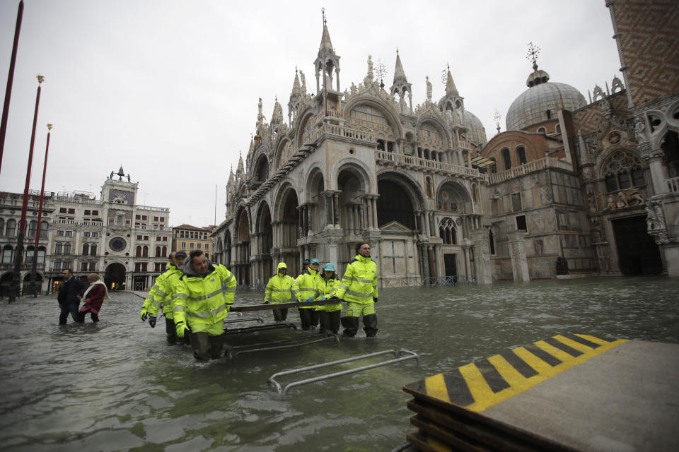 Municipality workers carry wooden boards to create a trestle bridge in a flooded St. Mark's Square at Venice, Friday, Nov. 15, 2019.The high-water mark hit 187 centimeters (74 inches) late Tuesday, Nov. 12, 2019, meaning more than 85% of the city was flooded. The highest level ever recorded was 194 centimeters (76 inches) during infamous flooding in 1966. (AP Photo/Luca Bruno)