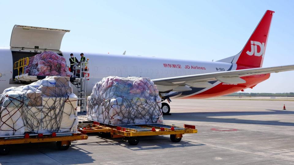 Loading cargo pallets onto a JD Airlines red tail plane.