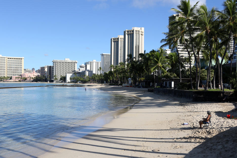 FILE - In this Oct. 2, 2020, file photo, a man sits on Waikiki Beach in Honolulu. Honolulu is loosening some restrictions on social activity now that more than half its population has been vaccinated against COVID-19. The new rules allow outdoor social gatherings of up to 25 people and indoor gatherings of up to 10.(AP Photo/Caleb Jones, File)