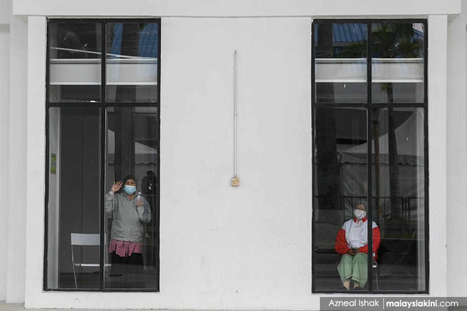 A patient at the Covid-19 Quarantine and Low-Risk Treatment Centre in Serdang waves to photographers through a window on Jan 16, 2021. The centre, located at the Malaysia Agro Exposition Park Serdang (Maeps) is capable of accommodating up to 10,000 beds.