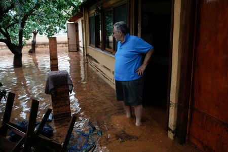 Meletis Rigos, 63, stands at the entrance of his flooded house, following flash floods which hit the town of Magoula, Greece, June 27, 2018. REUTERS/Costas Baltas