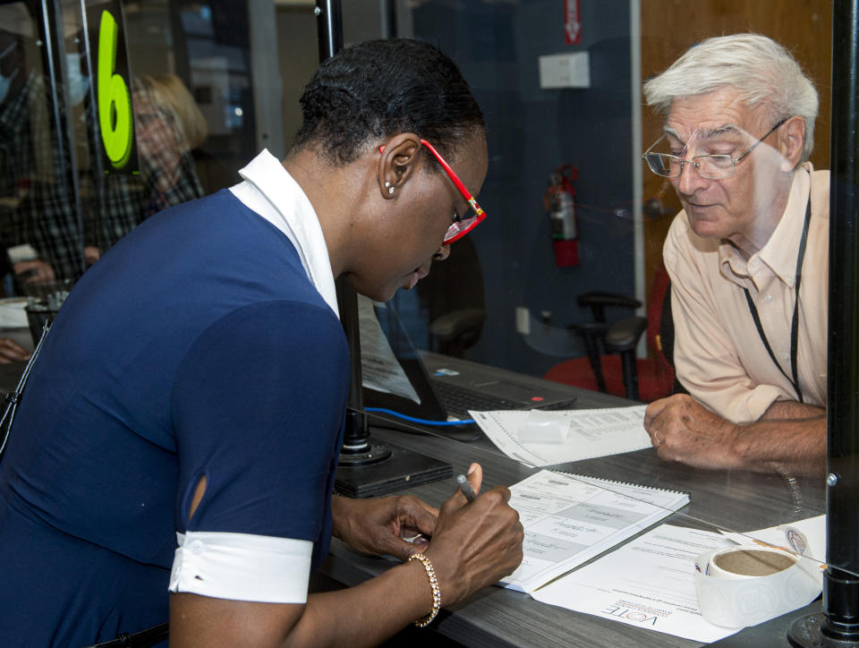 In this July 7, 2021, photo Nina Turner, a candidate running in a special Democratic primary election for Ohio's 11th Congressional District signs in as election official Fred Smith looks on at the Cuyahoga County Board of Elections before casting her vote in Cleveland. (AP Photo/Phil Long)