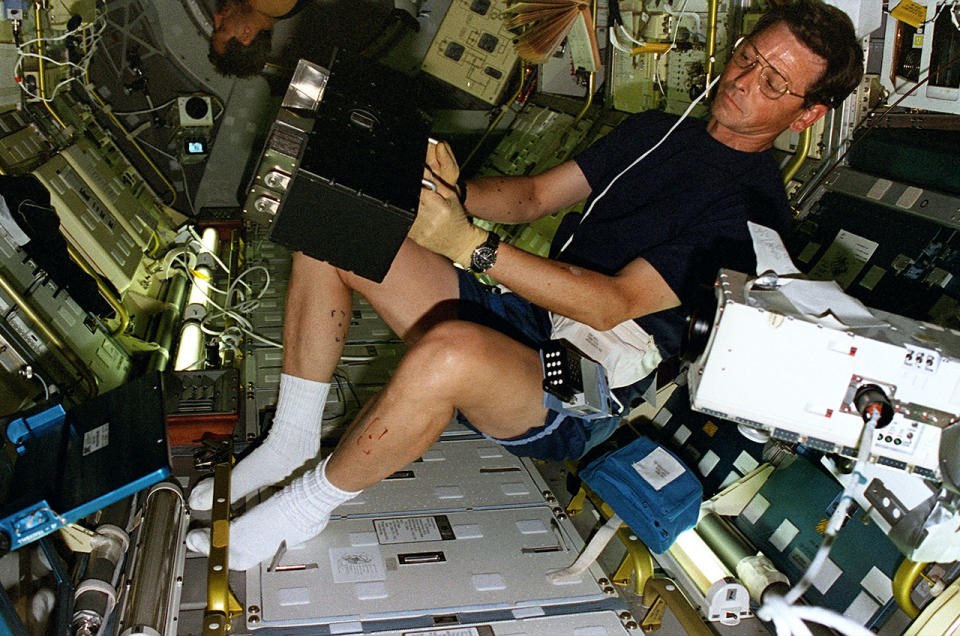  STS-78 payload specialist Jean-Jacques Favier, representing the French space agency CNES, holds up a Bubble Drop Particle Unit test container to a camera inside the Spacelab module aboard the space shuttle Columbia in July 1996. 