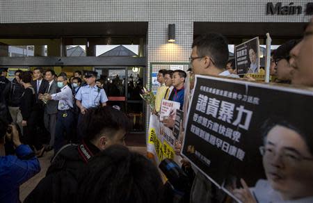 Hong Kong Chief Executive Leung Chun-ying (centre L) leaves a hospital after checking the condition of former Ming Pao chief editor Kevin Lau Chun-to as protesters carrying portraits of Lau demonstrate in Hong Kong February 26,2014. REUTERS/Tyrone Siu