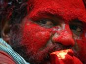 A devotee, with coloured powder smeared on his face, holds a piece of pumpkin as part of an offering while taking part in the annual Hindu religious festival of "Bonalu" in the southern Indian city of Hyderabad July 18, 2011. Devotees believe that the offerings ward off evils and epidemics during the monsoon period. REUTERS/Krishnendu Halder