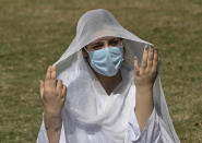 A Kashmiri student hold her veil to protect from sun as along-with other colleagues attend school in the open Srinagar, Indian controlled Kashmir, Monday, Sept. 21, 2020. Schools on a voluntary basis for classes 9 to 12 reopened in Indian-controlled Kashmir, five months after educational institutions were closed due to the coronavirus lockdown. (AP Photo/Mukhtar Khan)