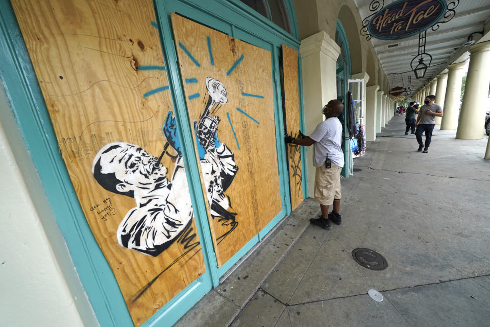 Workers board up shops in the French Quarter of New Orleans, Sunday, Aug. 23, 2020, in advance of Hurricane Marco, expected to make landfall on the Southern Louisiana coast. (AP Photo/Gerald Herbert)