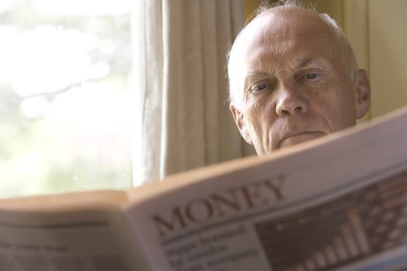 A retired man reading the money section of a newspaper.