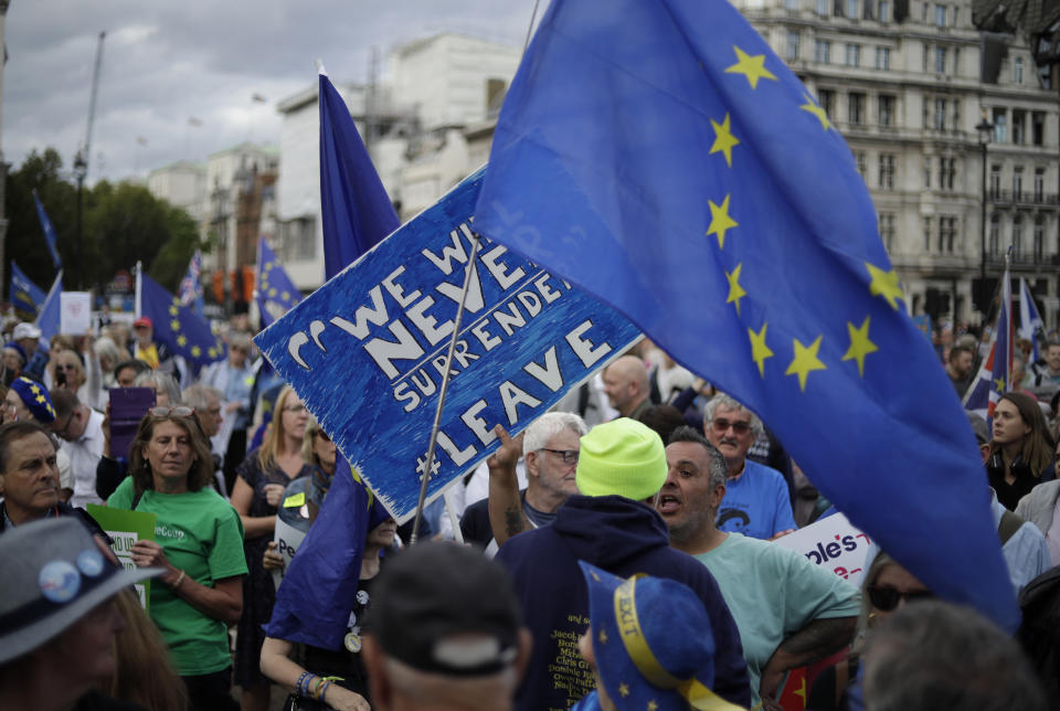 A leave supporter, left holding sign, tussles with a remain supporter, right holding EU flag, during a demonstration on Parliament Square in London, Wednesday, Sept. 4, 2019. With Britain's prime minister weakened by a major defeat in Parliament, defiant lawmakers were moving Wednesday to bar Boris Johnson from pursuing a "no-deal" departure from the European Union. (AP Photo/Matt Dunham)