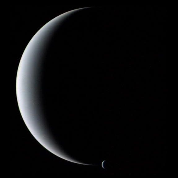 The crescent planet Neptune and its crescent moon Triton, as seen by NASA's Voyager 2 spacecraft in 1989.