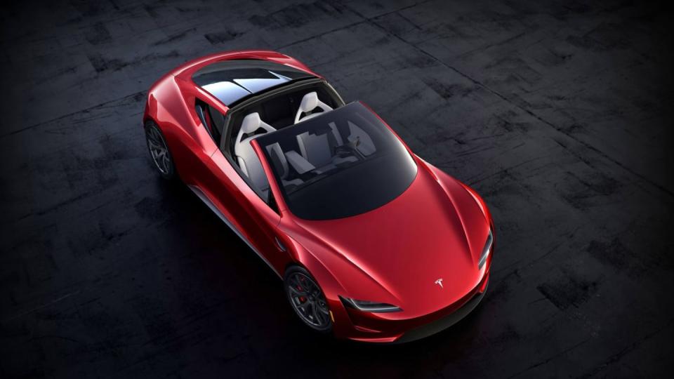 a red two door tesla sports car is shown from above sitting on black tarmac